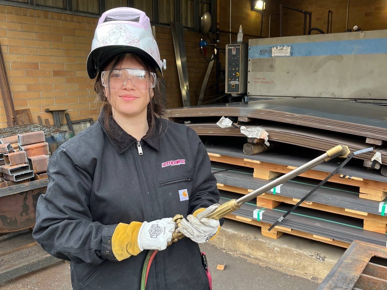 Shelsy smiling with welding torch