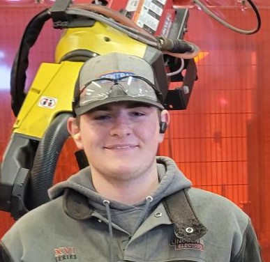 RTC student Mason Nelson smiling standing in front of machinery