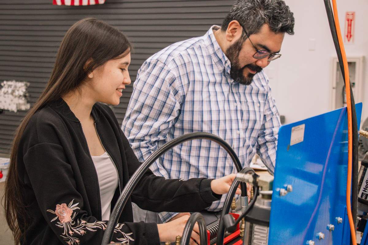 A student and an instructor working at a mechatronics station.