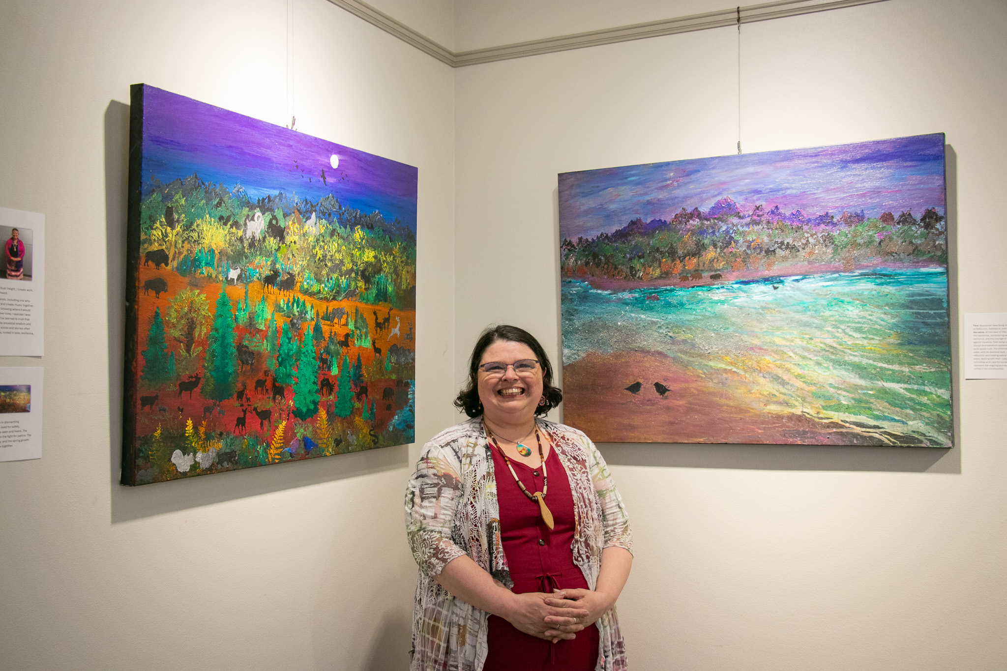 Maizy Bear posed next to two of her paintings