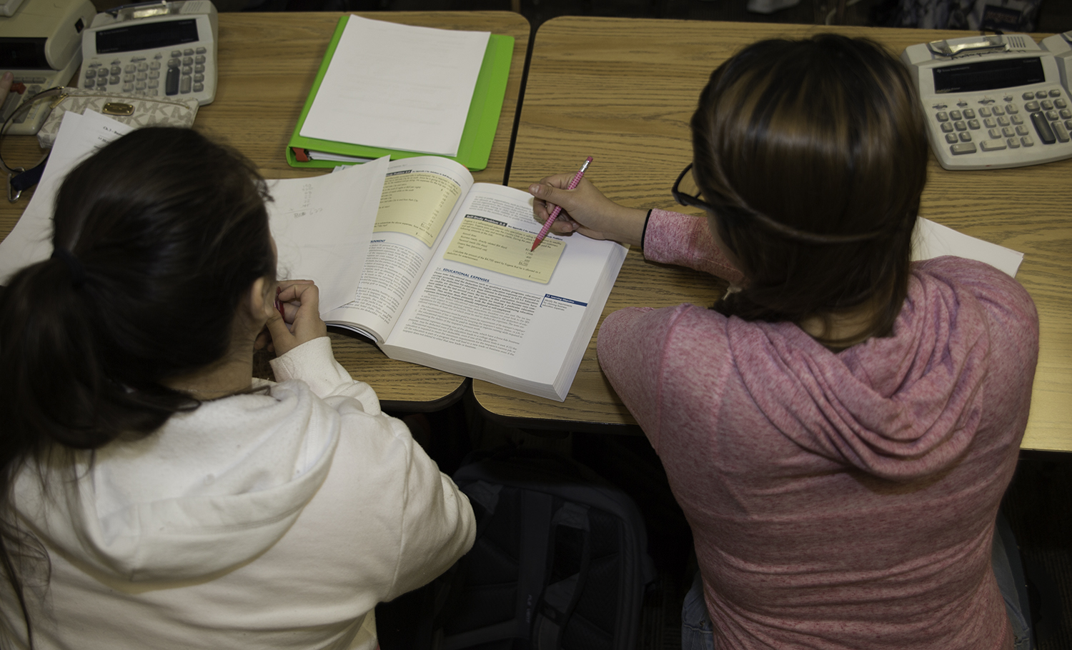Two people reading a textbook together.