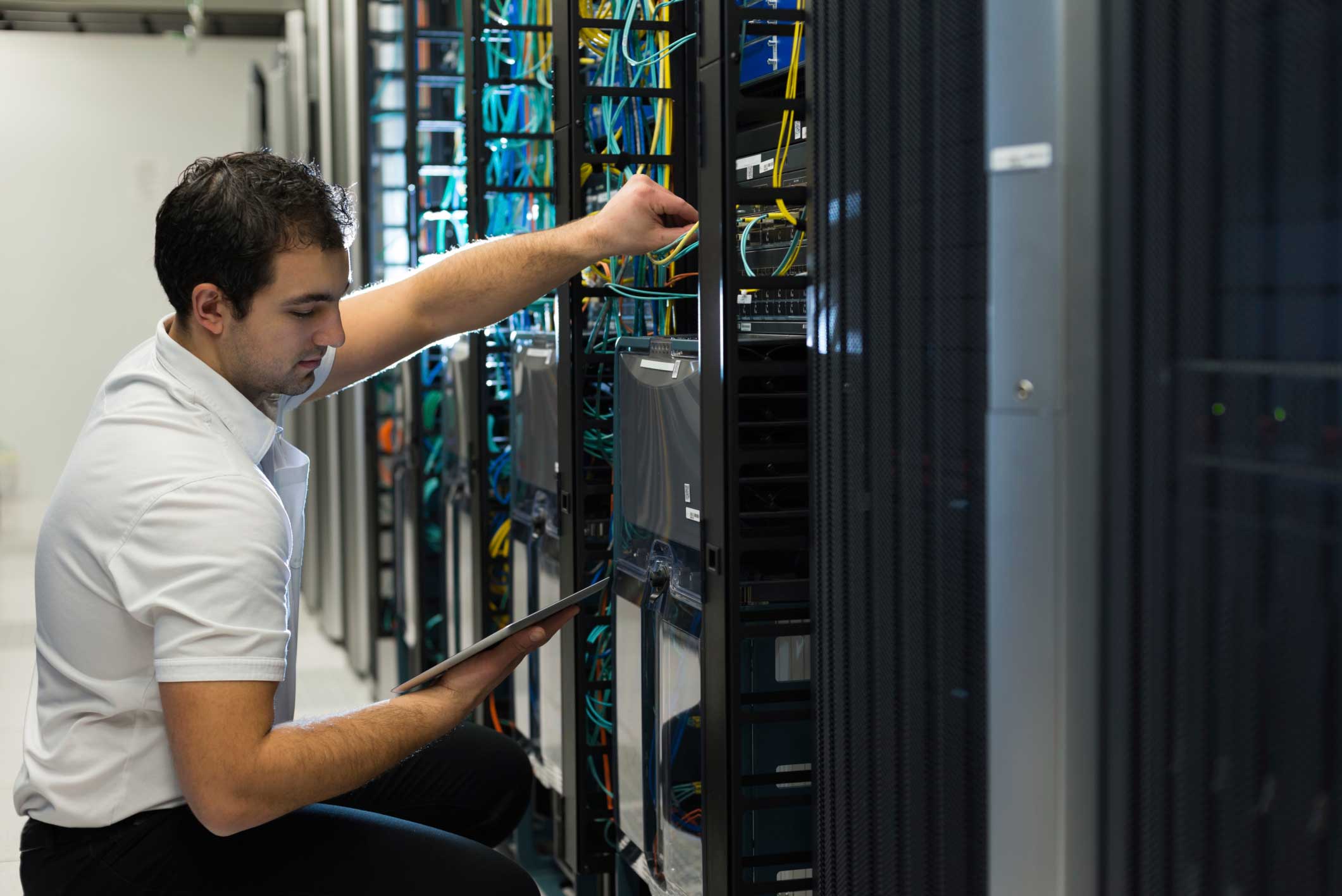 A man holding a tablet working on a server.