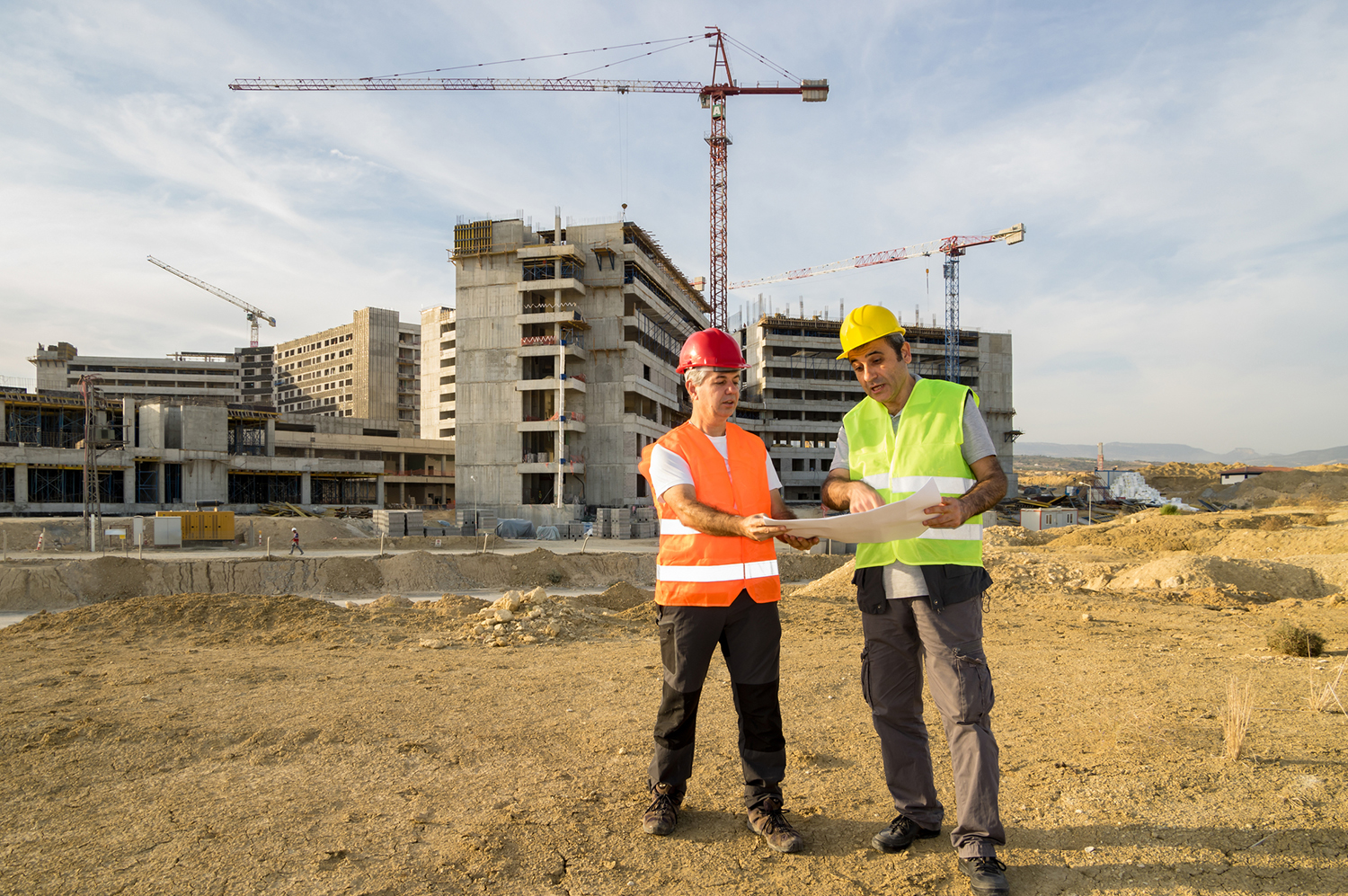 Two construction workers reading blueprints on a construction site.