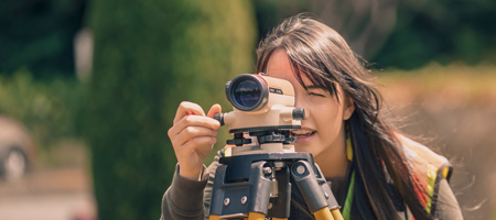 Student using a land surveying scope tripod tool