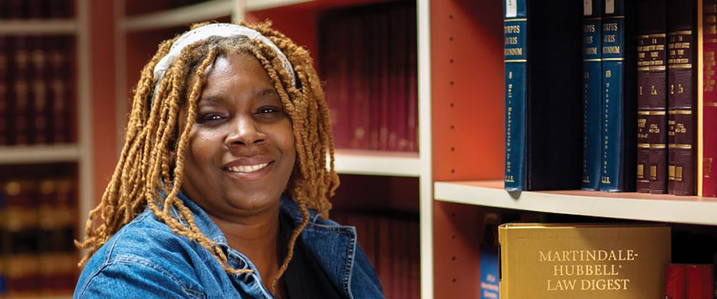 A woman standing in front of legal books.