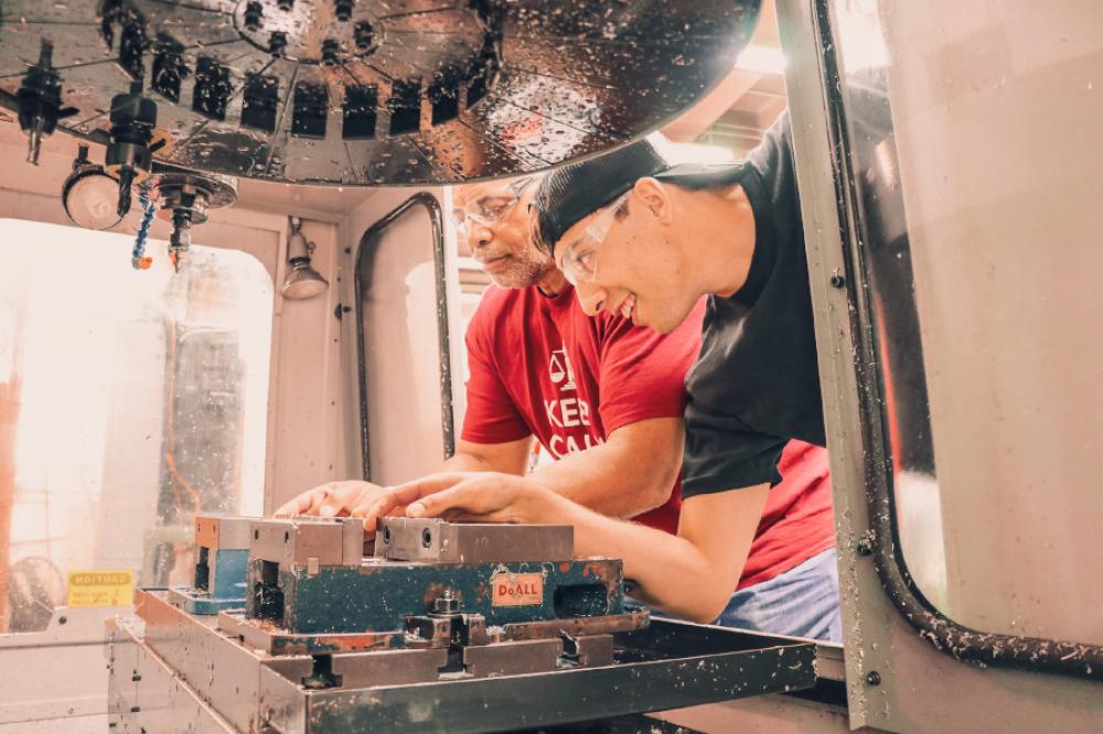Two men working inside of a machine.