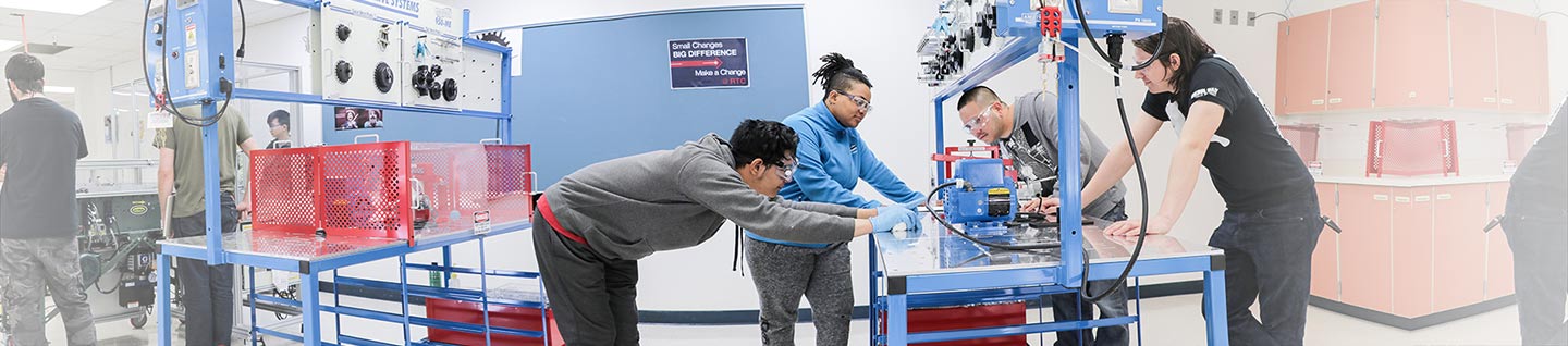 A group of mechatronics students inspecting a device on a table.