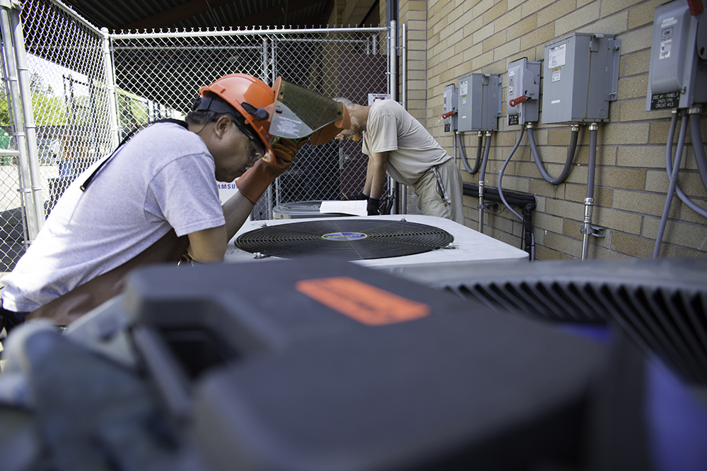 Two men working on an air conditioning unit.