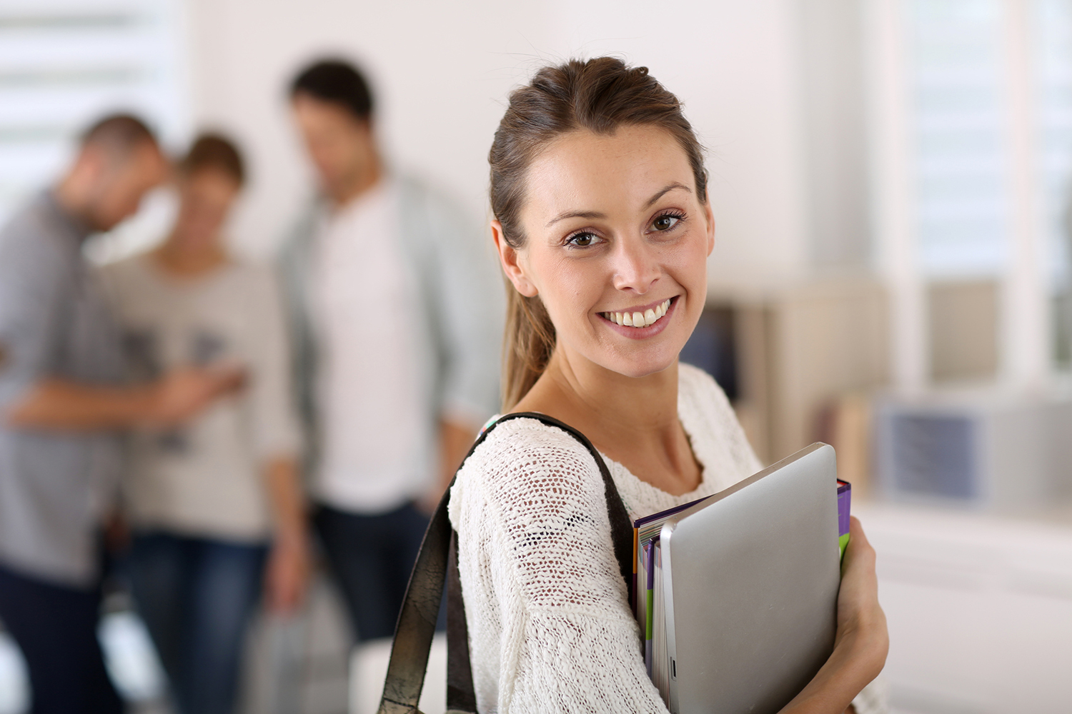 A student holding a laptop smiling.