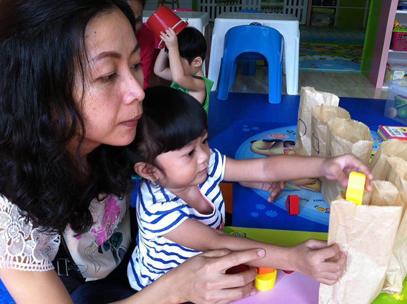 Photo of RTC alumnus, Supunnee Pargul, helps one of her students tackle a craft project.