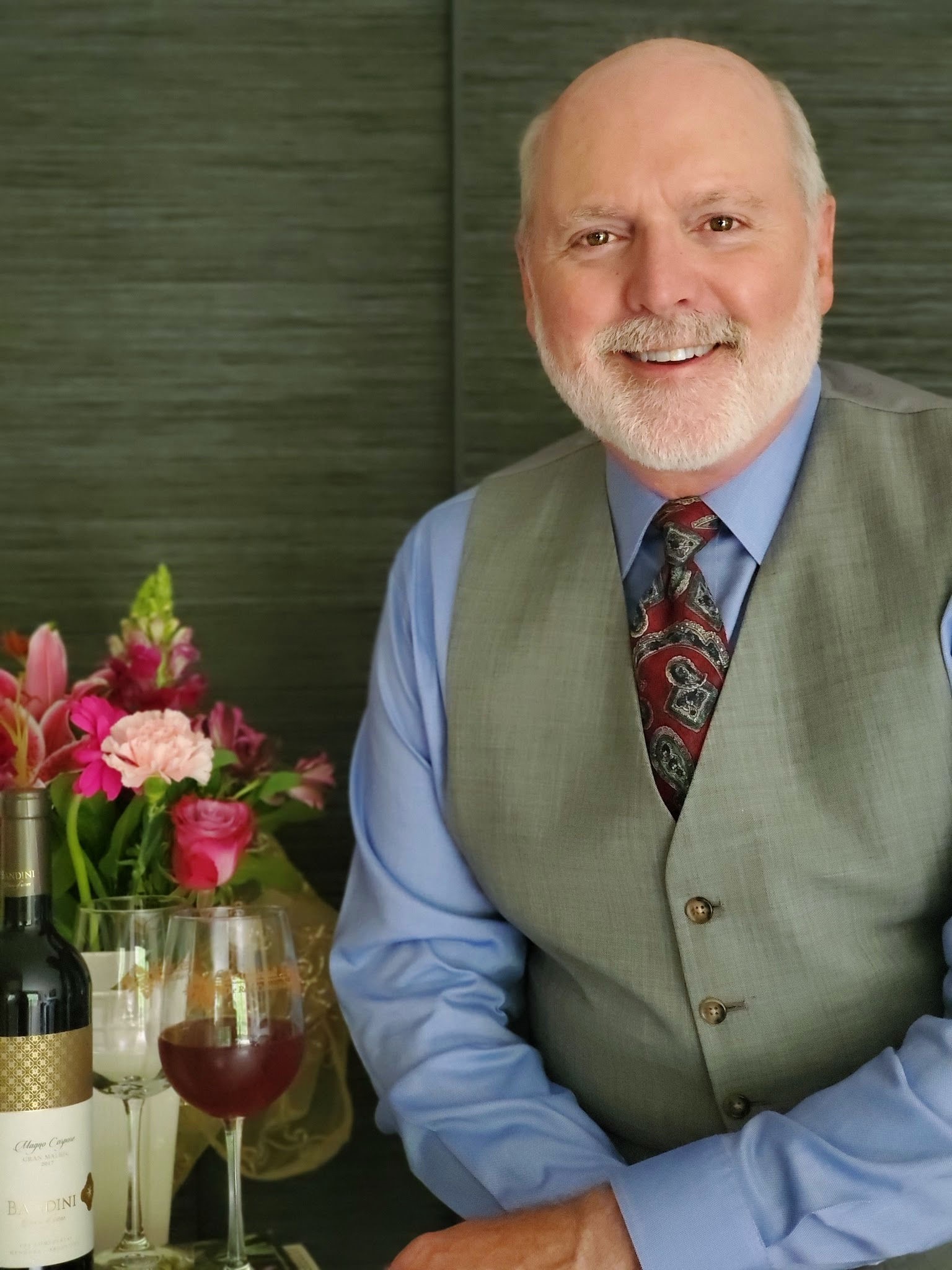 Sommelier Bruce Sturgeon Sommlier Bruce Sturgeon smiling and seated in front of wine bottles