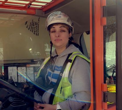 Leilanna Barrientes operating a backhoe with hardhat