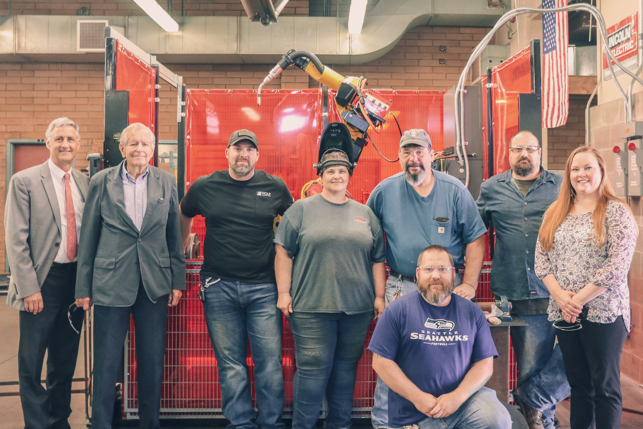 Welding class with RTC President, Mr. Piggot, and others in front of the welding robot