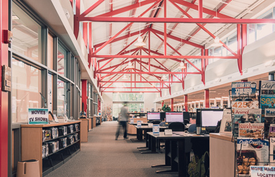 Inside the RTC library; a person walking, motion blurred, walking past the computers, books, and magazines